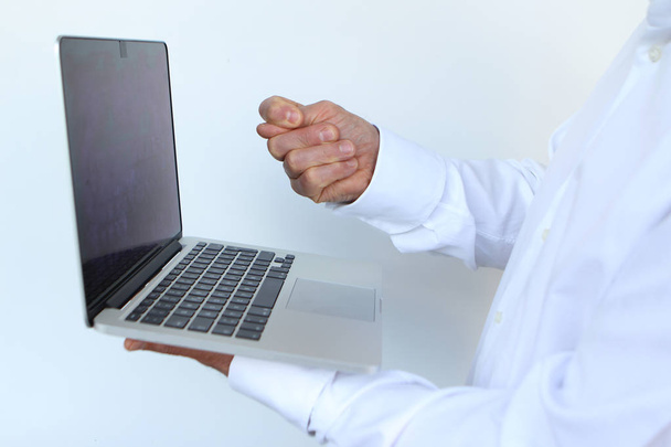 businessman in a white shirt with a laptop in hand, showing a blow to the monitor, close-up, copy space - 写真・画像