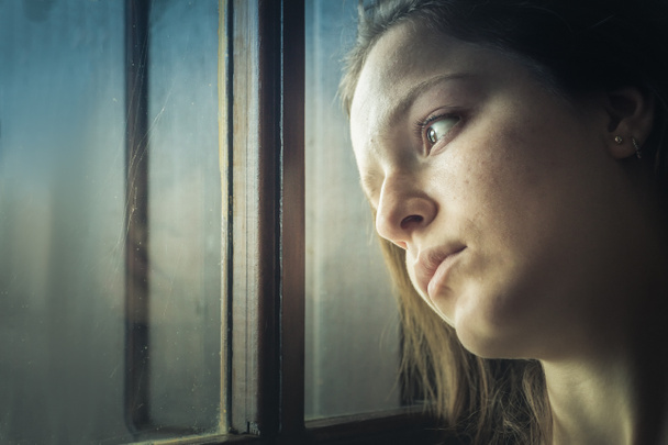 Retrato de uma adolescente pensando, triste, olhando para longe ao lado de uma janela
. - Foto, Imagem