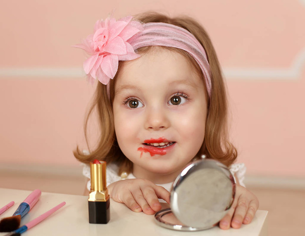 girl with mirror painting mom lipstick - Foto, imagen