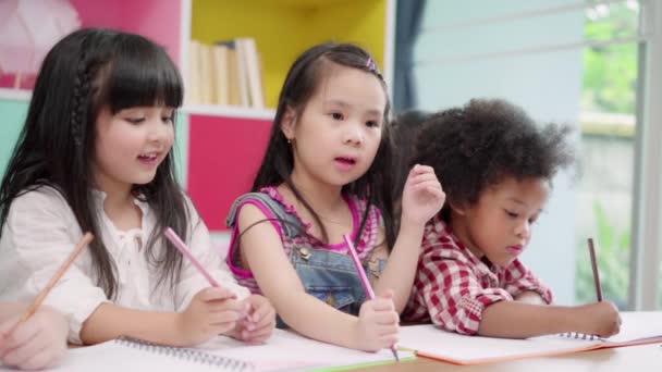 Zeitlupe - eine Gruppe von Kindern, die im Klassenzimmer zeichnen, multiethnische Jungen und Mädchen, die in der Grundschule fröhlich lernen und malen. Kinder zeichnen und malen im Schulkonzept. - Filmmaterial, Video