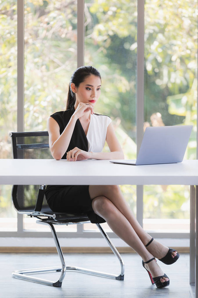 Ασιάτισσα επιχειρηματίας που κοιτάζει φορητό υπολογιστή στο γραφείο - Φωτογραφία, εικόνα