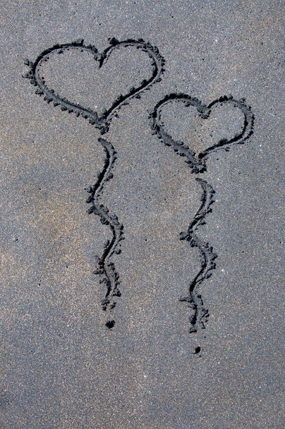 Сердце формирует воздушные шары на черном песке
 - Фото, изображение