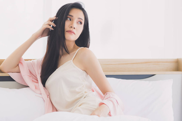  Aasialainen nainen malli istuu ja poseeraa sängyssä
 - Valokuva, kuva