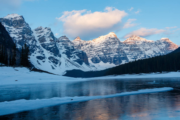 Moraine Lake Frozen with snowy Mountains at sunrise - Photo, Image