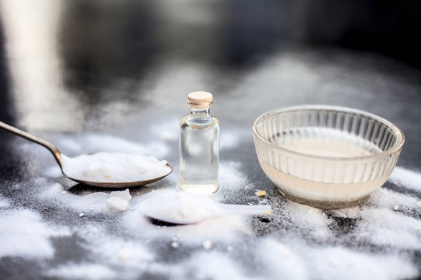 Face mask or face pack of baking soda in a glass bowl on wooden surface along with powder and some coconut oil in a transparent glass bottle. Used for rashes. Horizontal shot. - Foto, imagen