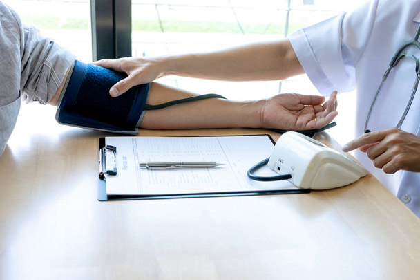 lékař sedět test tlakoměr a vyšetření na pacienta - Fotografie, Obrázek