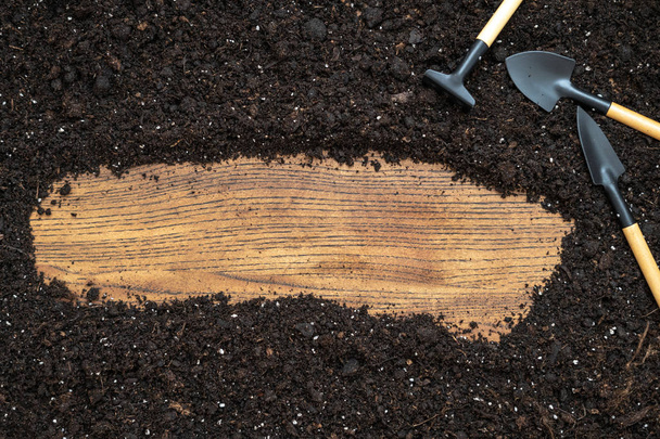 Vista superior de conjunto de ferramentas de jardinagem, ancinho, pá e no texto de madeira
 - Foto, Imagem