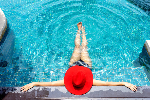 Asiatische Frau mit rotem Hut entspannen auf Schwimmbad.  - Foto, Bild