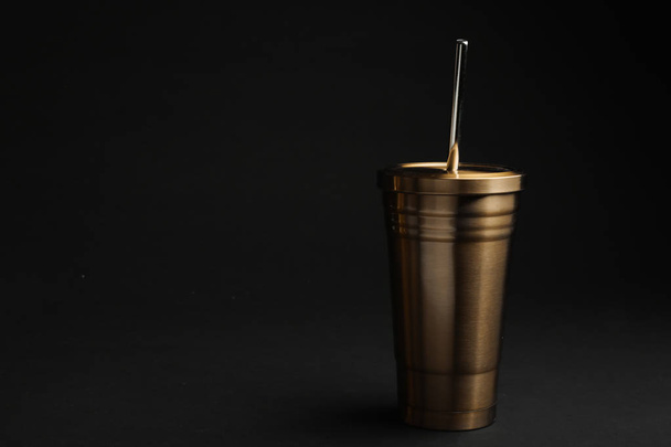 Gold cup with straw on black background. Space for text - Photo, image