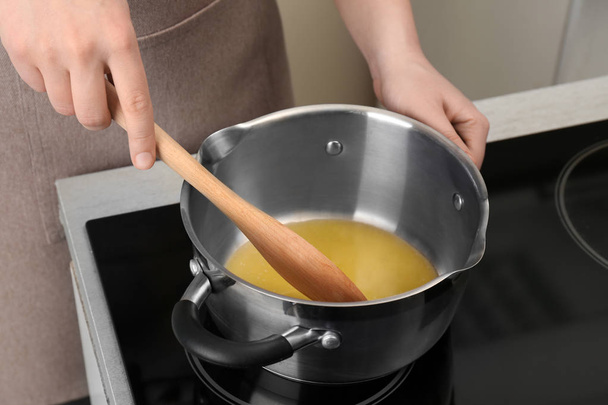 Woman stirring butter in saucepan on electric stove, closeup - Foto, imagen