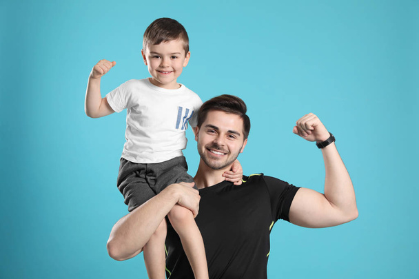Portrait of sporty dad and his son on color background - Fotó, kép