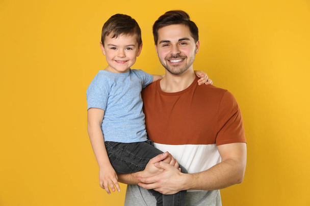 Portrait of dad and his son on color background - Фото, зображення