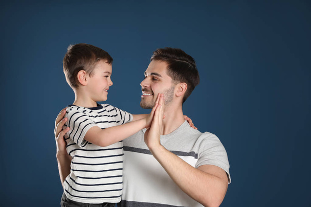 Portrait of dad and his son giving high five on color background - Photo, image