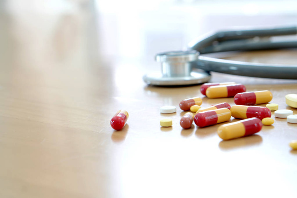 pojęcie medyczne tabletki i na stół drewniany stetoskop - Zdjęcie, obraz