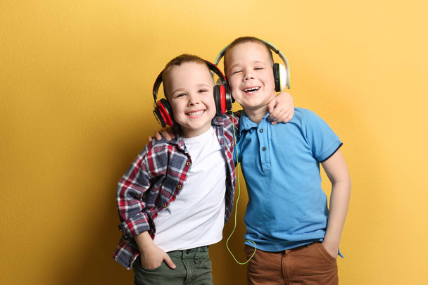 Portrait of cute twin brothers with headphones on color background - Zdjęcie, obraz