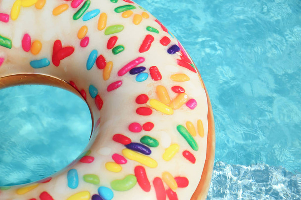 Bright inflatable doughnut ring floating in swimming pool on sunny day. Space for text - Foto, immagini