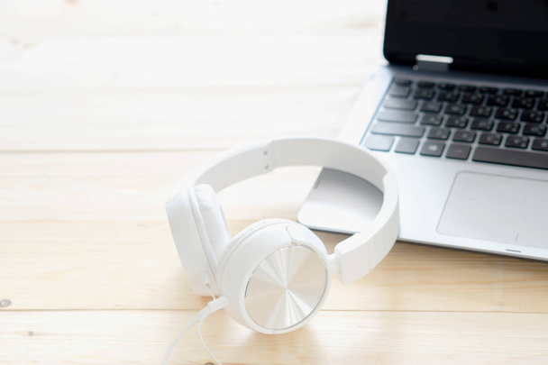 White headphone and laptop computer on wooden background - 写真・画像