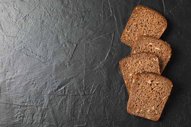 Rye bread pieces on black background, top view and space for tex - Photo, image