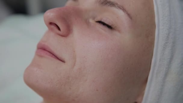professionelle Kosmetikerin trägt das Serum auf das Gesicht der Patienten auf. - Filmmaterial, Video