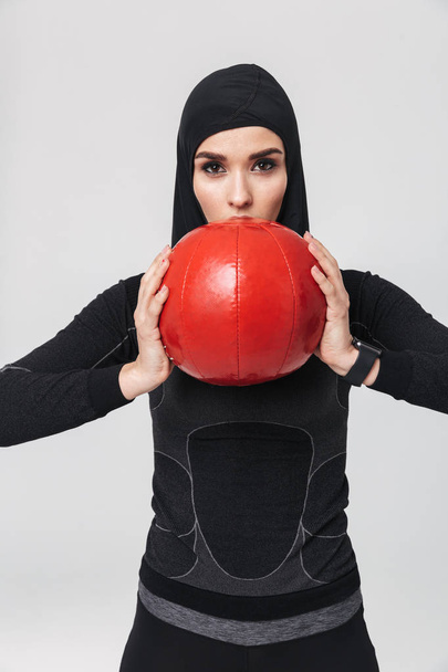 Nainen kunto muslimi poseeraa yli valkoinen seinä tausta tehdä harjoituksia pallo
. - Valokuva, kuva
