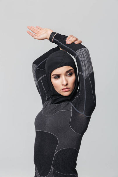 Young woman fitness muslim make stretching exercises isolated over white wall background. - Фото, изображение