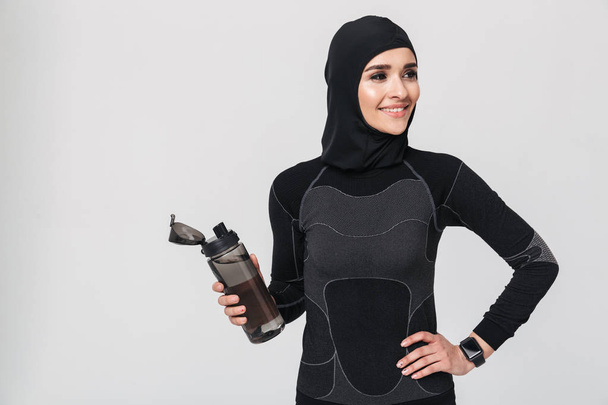 Fitness muslim isolated over white wall background drinking water. - 写真・画像