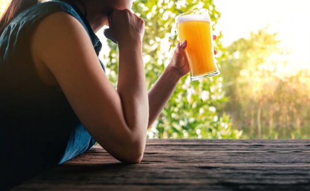 Vrouwelijke drinken bier concept. Vrouw ontspannen door glas bier op balkon in de zomer - Foto, afbeelding