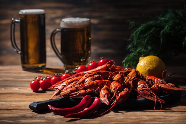 selective focus of red lobsters, tomatoes, dill, lemon and glasses with beer on wooden surface - Φωτογραφία, εικόνα