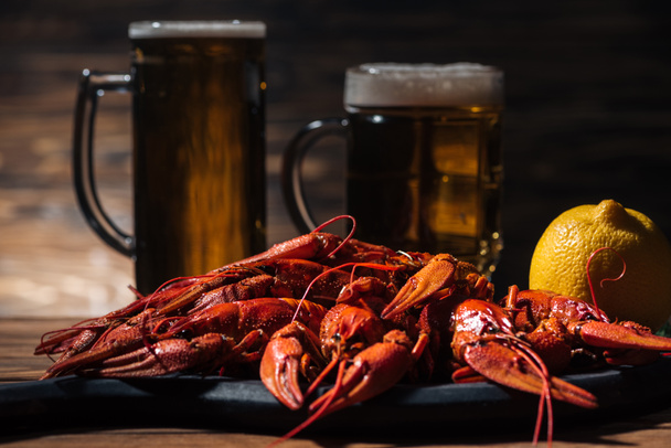 selective focus of red lobsters, lemon and glasses with beer on wooden surface - Photo, Image