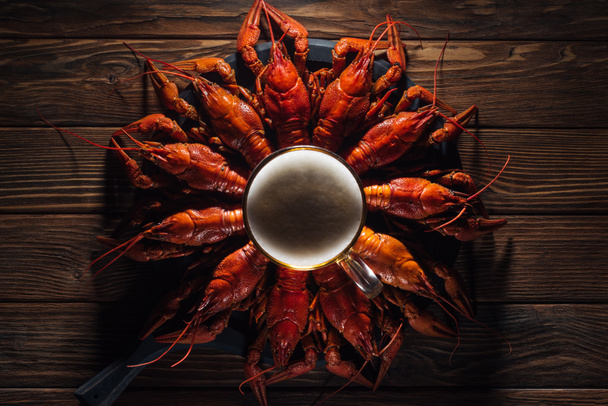 top view of glass of beer on plate with red lobsters at wooden surface - Foto, imagen