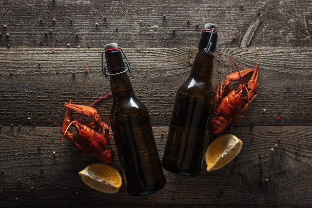 ylhäältä näkymä punaisia hummereita, sitruunaviipaleita ja pulloja oluella puupinnalla
 - Valokuva, kuva