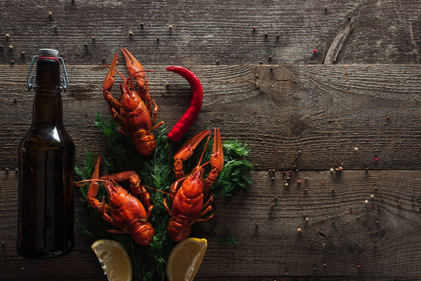 top view of red lobsters, lemon slices and dill on wooden surface - Photo, Image