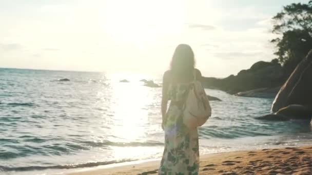 toeristisch meisje wandelen door de oceaan met een rugzak - Video
