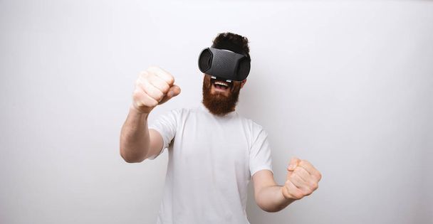 Hombre jugando y viendo a través de dispositivo VR aprender a conducir y estar emocionado
. - Foto, imagen