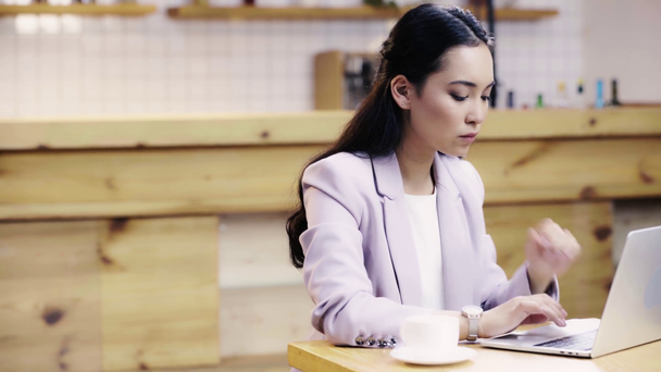 concentré et jolie asiatique femme d'affaires en costume de dactylographie sur ordinateur portable dans le café
  - Séquence, vidéo