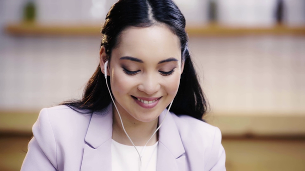 positivo y bonito asiático mujer en traje escuchar música en café
  - Metraje, vídeo