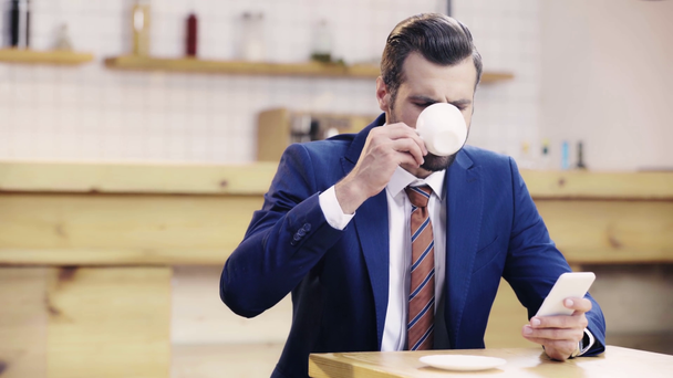 uomo d'affari bello e sorridente in giacca e cravatta bere caffè e utilizzando smartphone
  - Filmati, video