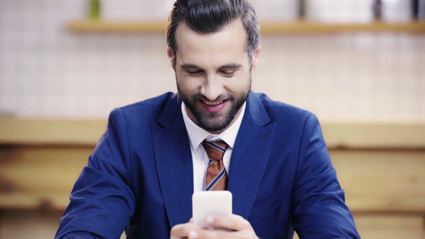 komea ja hymyilevä liikemies puku ottaen selfie ja käyttämällä älypuhelinta kahvilassa
  - Materiaali, video