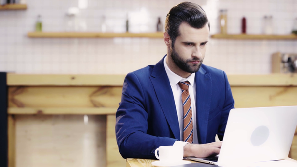 красивий і концентрований бізнесмен у костюмі, використовуючи ноутбук у кафе
  - Кадри, відео