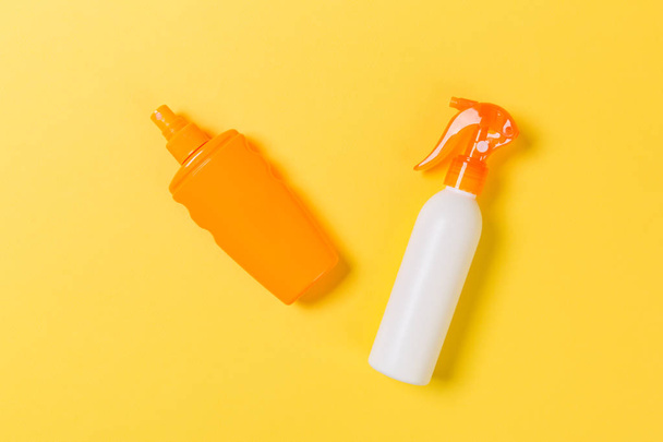 flat lay concept of summer travel vacation. Sunscreen bottle mock up on yellow background top view with copy space - Photo, Image