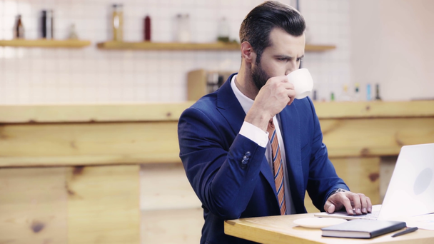 hombre de negocios guapo y sonriente en traje hablando en el teléfono inteligente, mirando el reloj en la cafetería
  - Metraje, vídeo