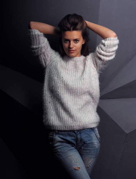 retrato de bela jovem mulher em suéter branco na frente da parede preta
 - Foto, Imagem