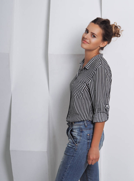 portrait of beautiful young woman in striped shirt in front of white wall - Фото, зображення