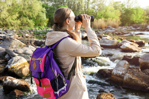 Turista femenina con binocular disfrutando de la belleza de la naturaleza
 - Foto, imagen