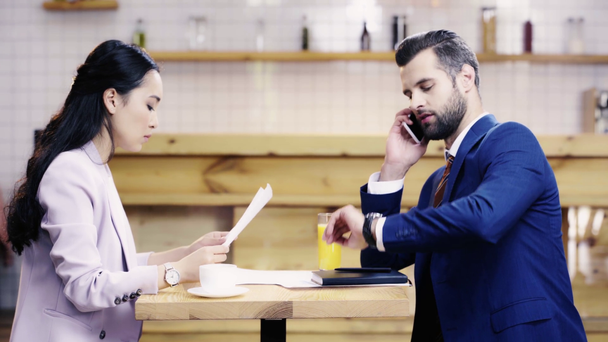 businesswoman holding papers, businessman writing in notebook, talking on smartphone and looking at watch  - Footage, Video