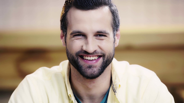 good-looking and brunette man looking at camera and smiling in cafe  - Filmmaterial, Video