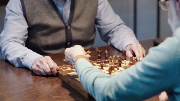cropped view of two senior men playing chess and pressing button on chess clock - Footage, Video