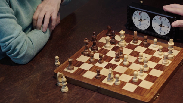 przycięte widok dwóch starszych mężczyzn gra w szachy i naciskając przycisk na Zegar szachowy - Materiał filmowy, wideo