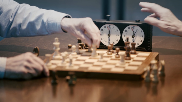 обрезанный вид двух старших мужчин, играющих в шахматы и нажатие кнопки на шахматных часах
 - Кадры, видео