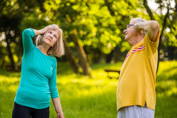 Senior couple is exercising in park. - Valokuva, kuva
